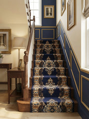 Tapis d'escalier bleu marine et or, à motifs classiques et complexes, habillant un escalier en bois dans un hall d'entrée raffiné
