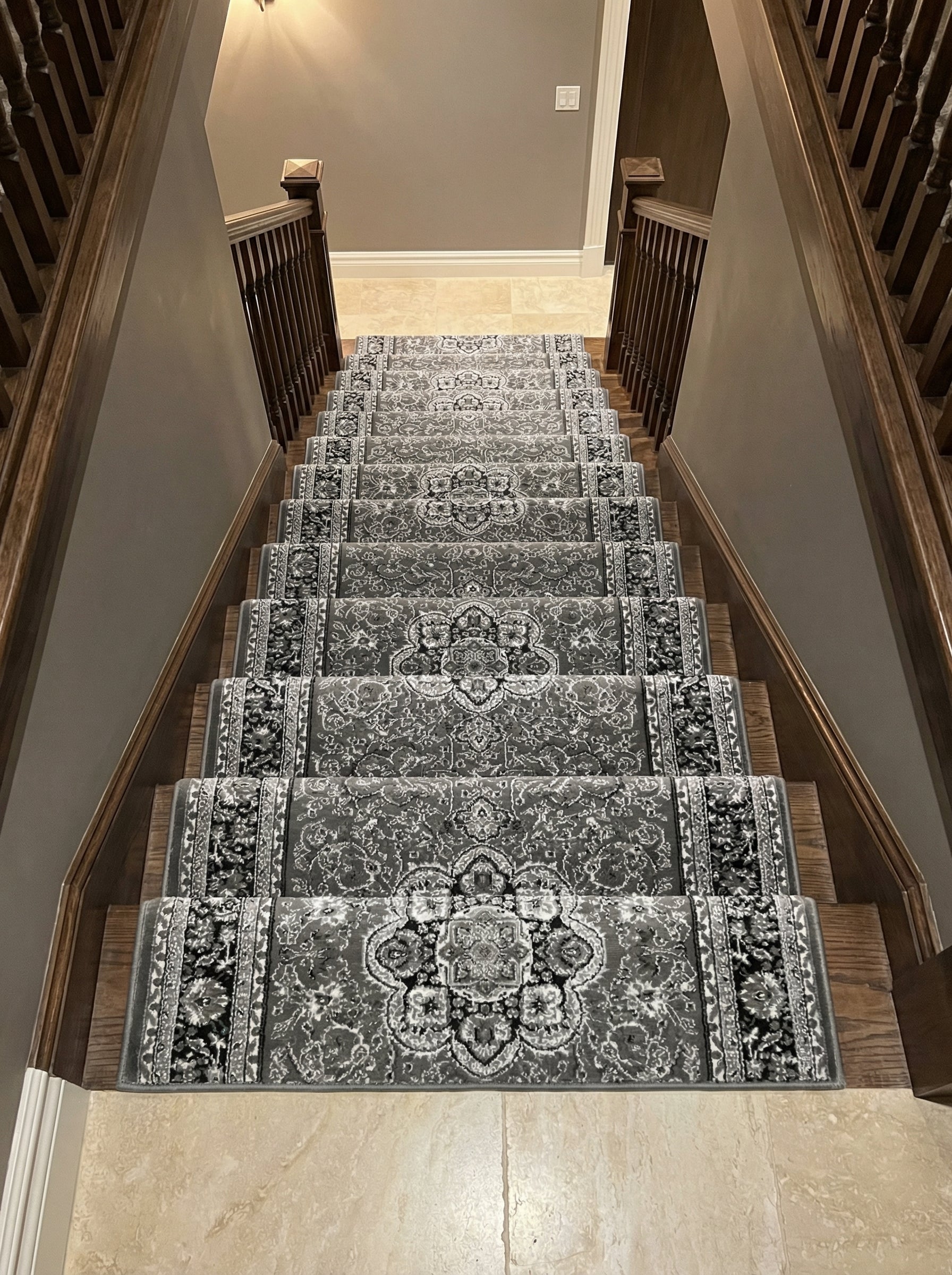 Tapis d'escalier gris et blanc à motifs ornementaux traditionnels sur des marches en bois, dans l'entrée d'une maison