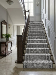 Tapis d'escalier gris foncé à motifs ornementaux floraux et médaillons noirs et clairs, installé dans une entrée élégante