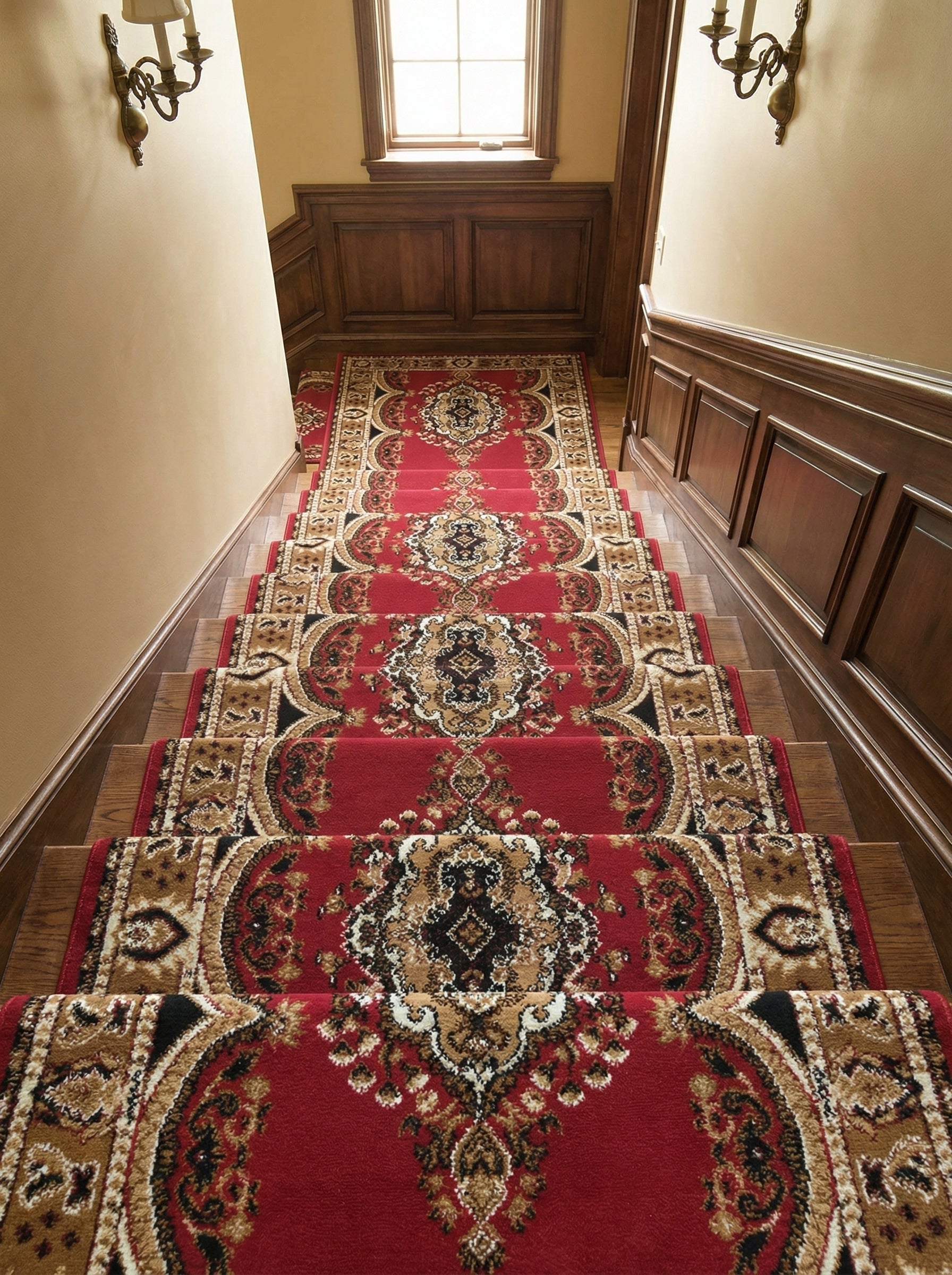 Tapis d'escalier rouge à motifs ornementaux riches en beige, marron et noir, garnissant une cage d'escalier élégante