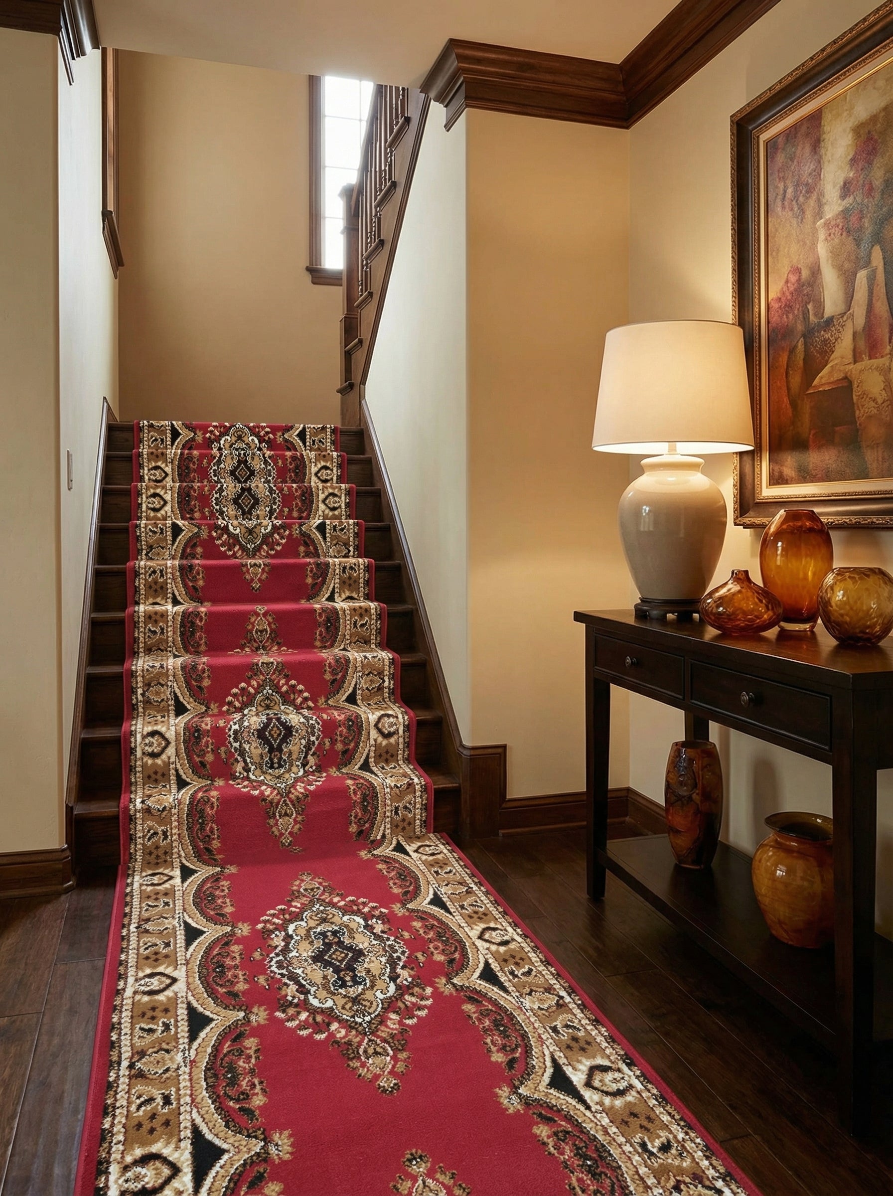 Tapis d'escalier rouge et or avec motifs orientaux complexes, descendant sur un plancher en bois foncé dans une entrée élégante