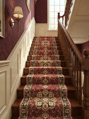 Tapis d'escalier rouge profond à motifs orientaux crème et noirs, couvrant des marches en bois dans un élégant hall d'entrée