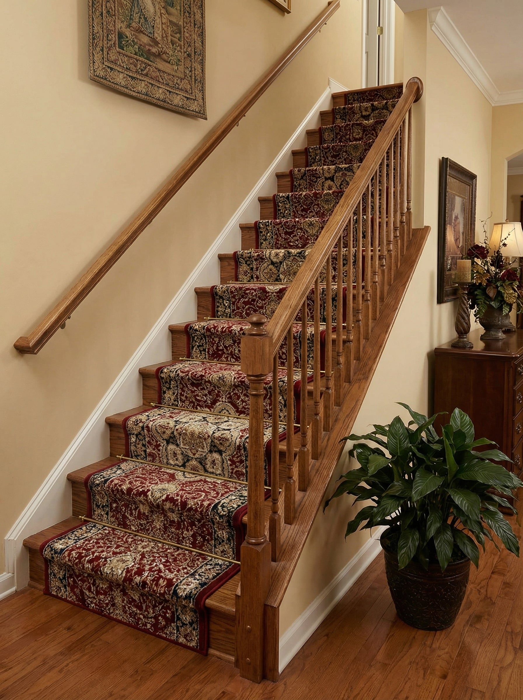 Un tapis d'escalier rouge bordeaux, orné de motifs floraux dorés et bleus, recouvre des marches en bois clair d'un hall