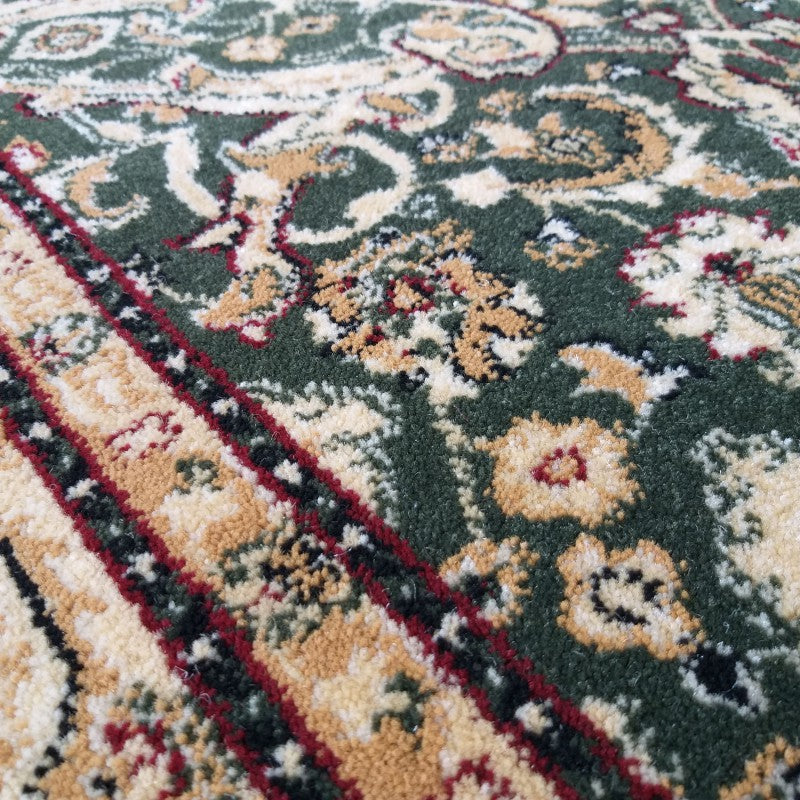Tapis aux motifs traditionnels vert foncé, beige, or et rouge, avec des détails floraux et des bordures rayées