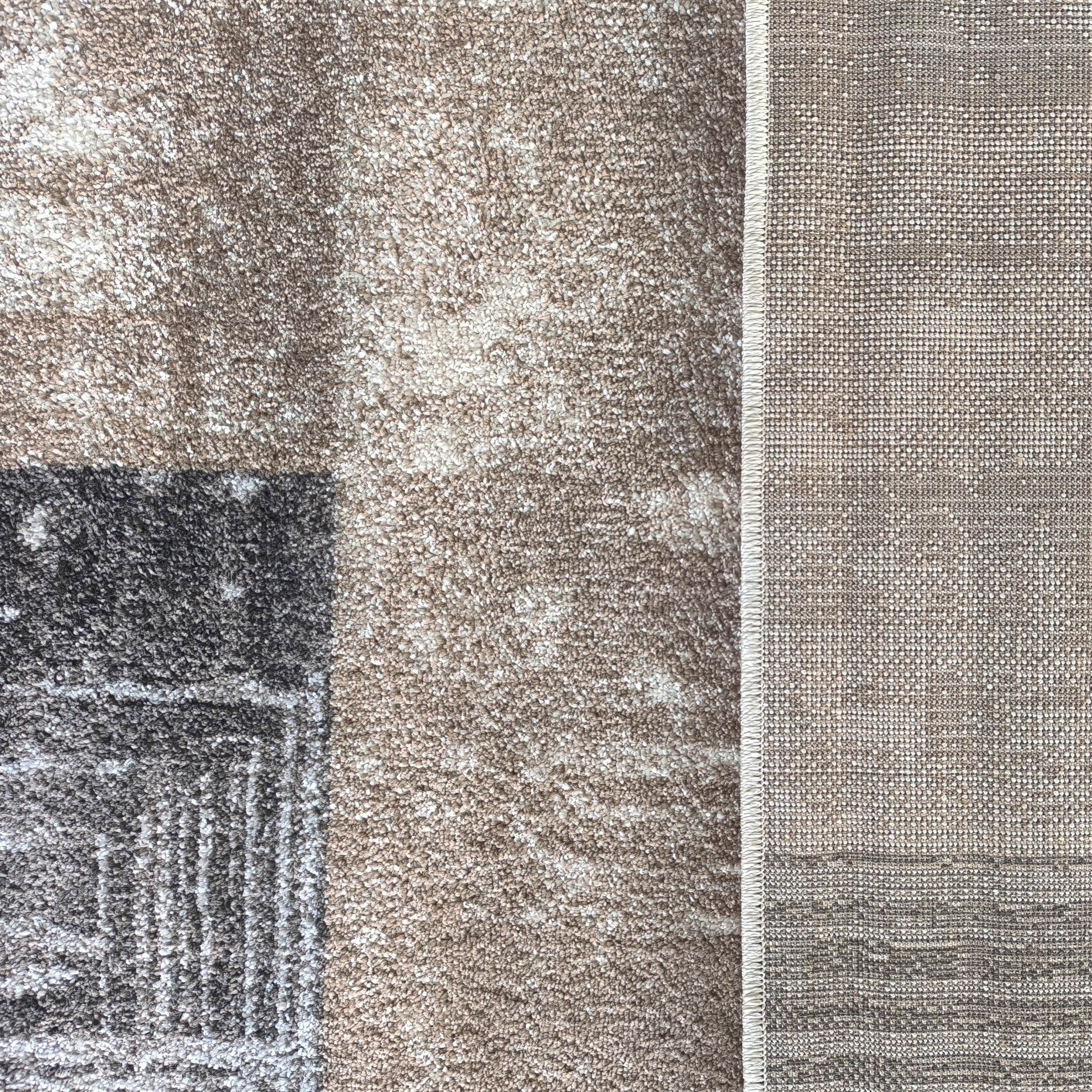 Tapis shaggy géométrique marron clair, blanc et gris foncé, près d'un tissu tissé beige et blanc à liseré clair