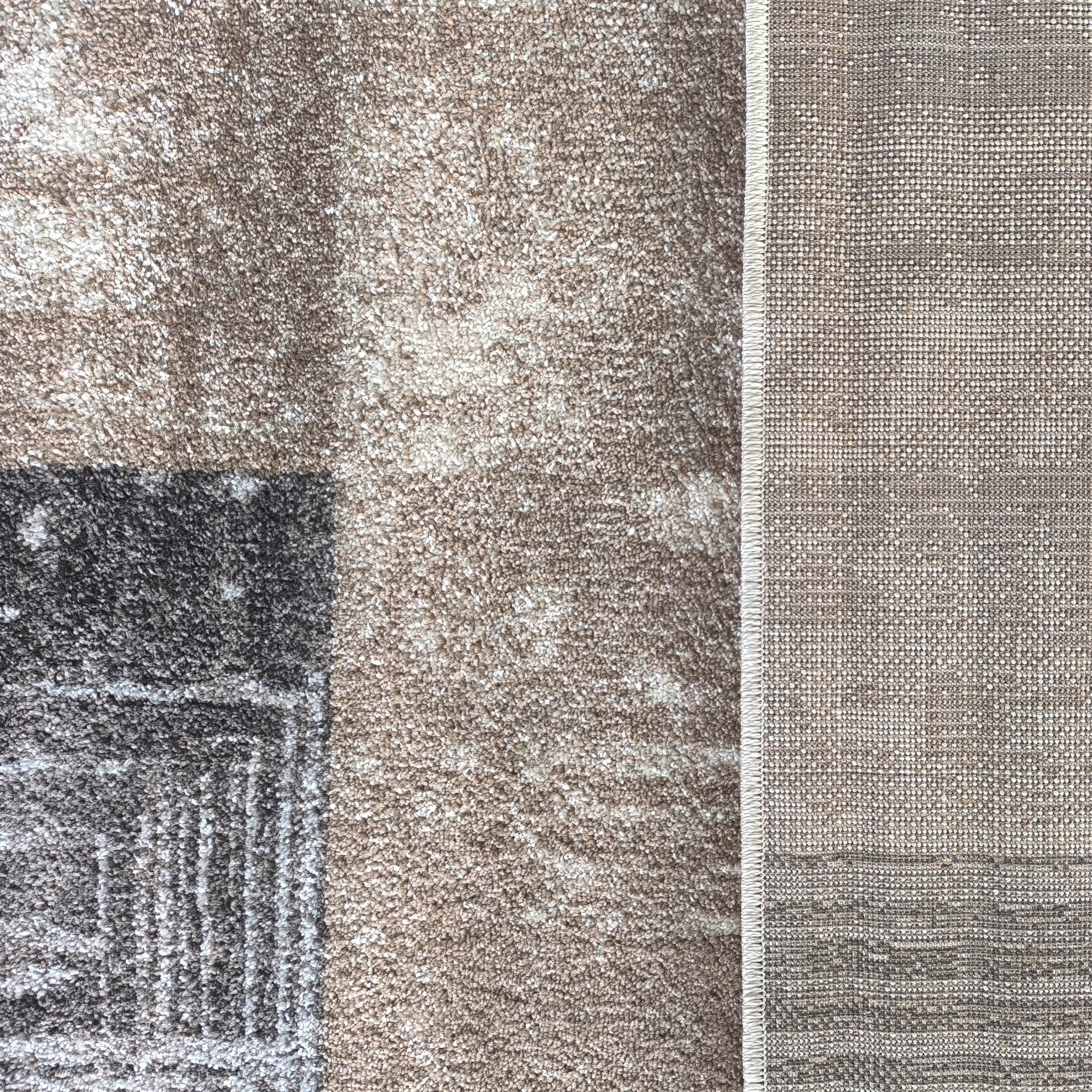 Tapis shaggy géométrique marron clair, blanc et gris foncé, près d'un tissu tissé beige et blanc à liseré clair