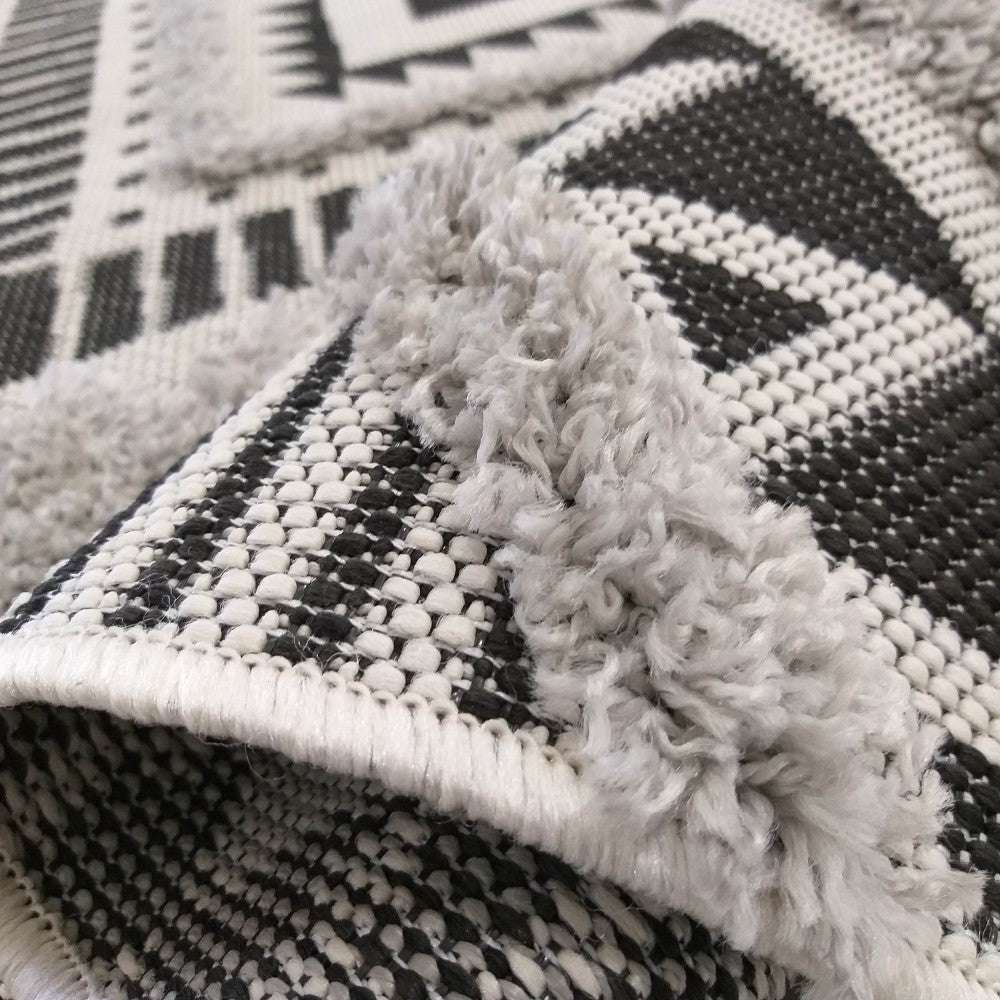 Tapis à motifs géométriques noirs et blancs, rehaussé de tufts gris épais
