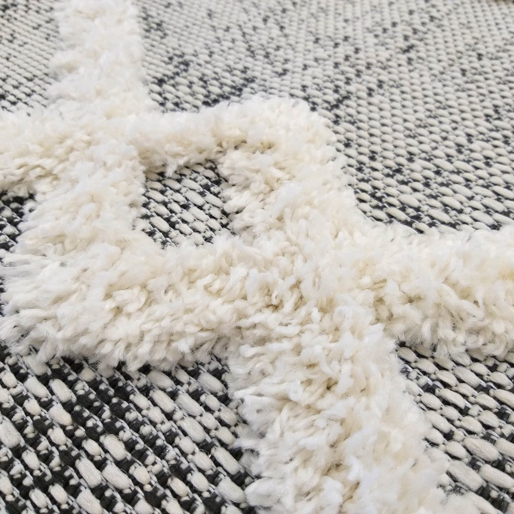 Tapis noir et blanc avec motifs géométriques en mèches longues et bouclées sur un fond tissé plat