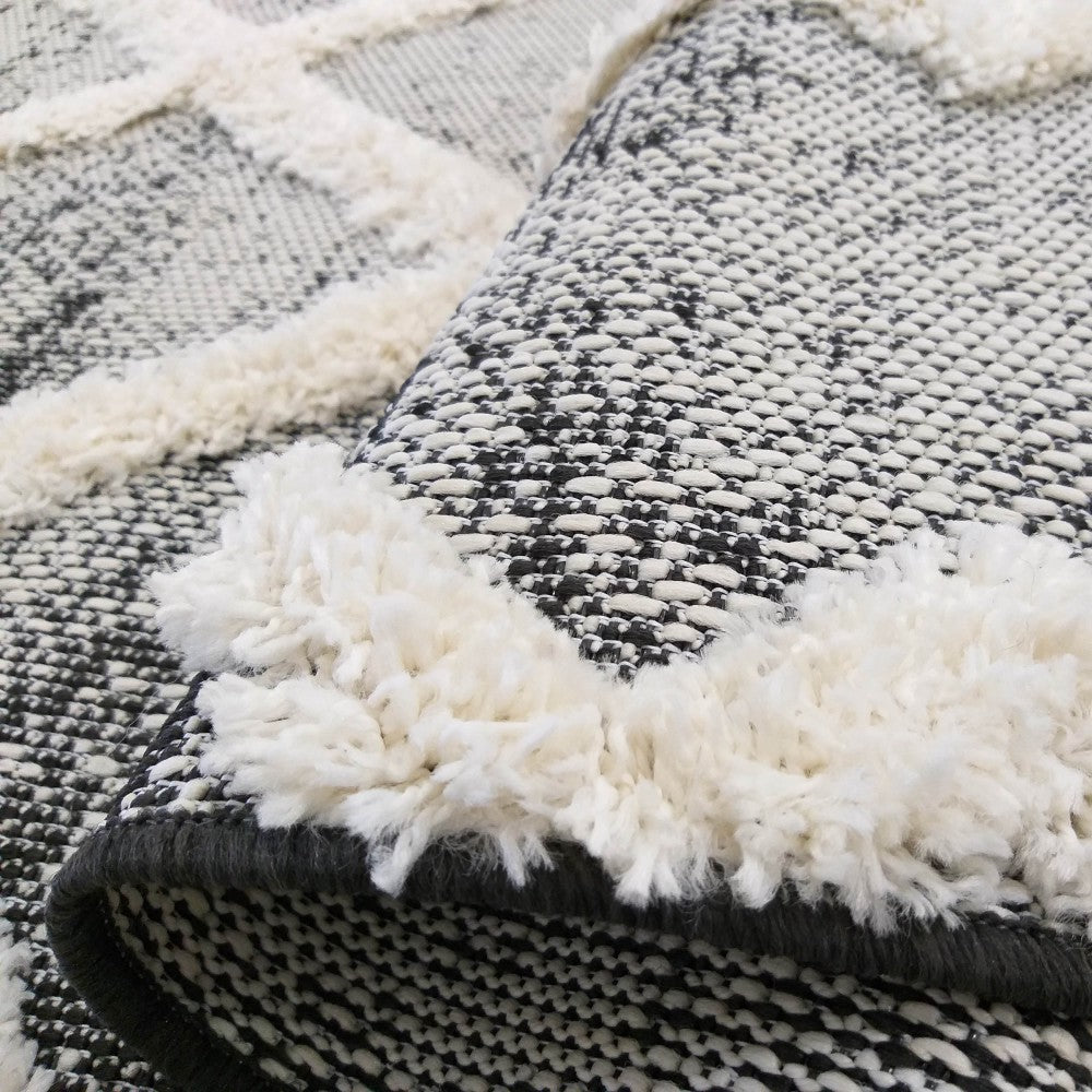 Tapis en gros plan, noir et blanc moucheté, orné de motifs géométriques en relief à la texture touffue crème