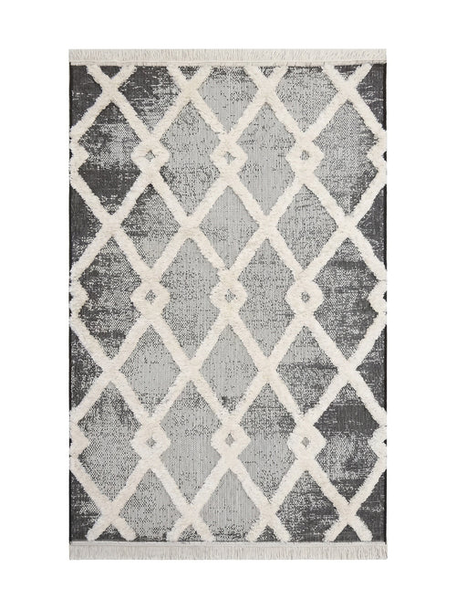 Tapis rectangulaire à motif de losanges géométriques en relief crème sur un fond texturé noir et blanc, avec des franges claires