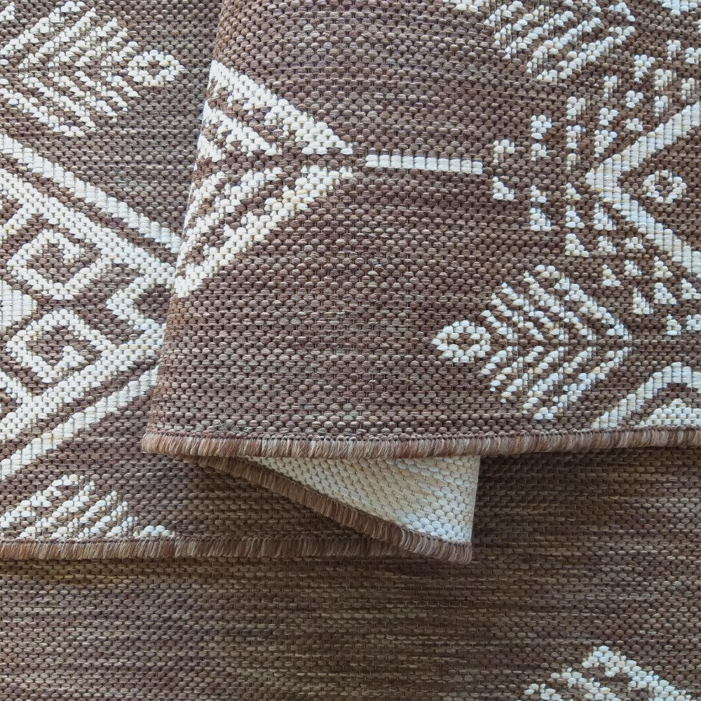 Tapis en textile tissé marron et écru présentant des motifs géométriques complexes, une bordure repliée visible