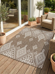 Tapis rectangulaire tissé marron et blanc avec des motifs géométriques ethniques de losanges et flèches, sur une terrasse en bois