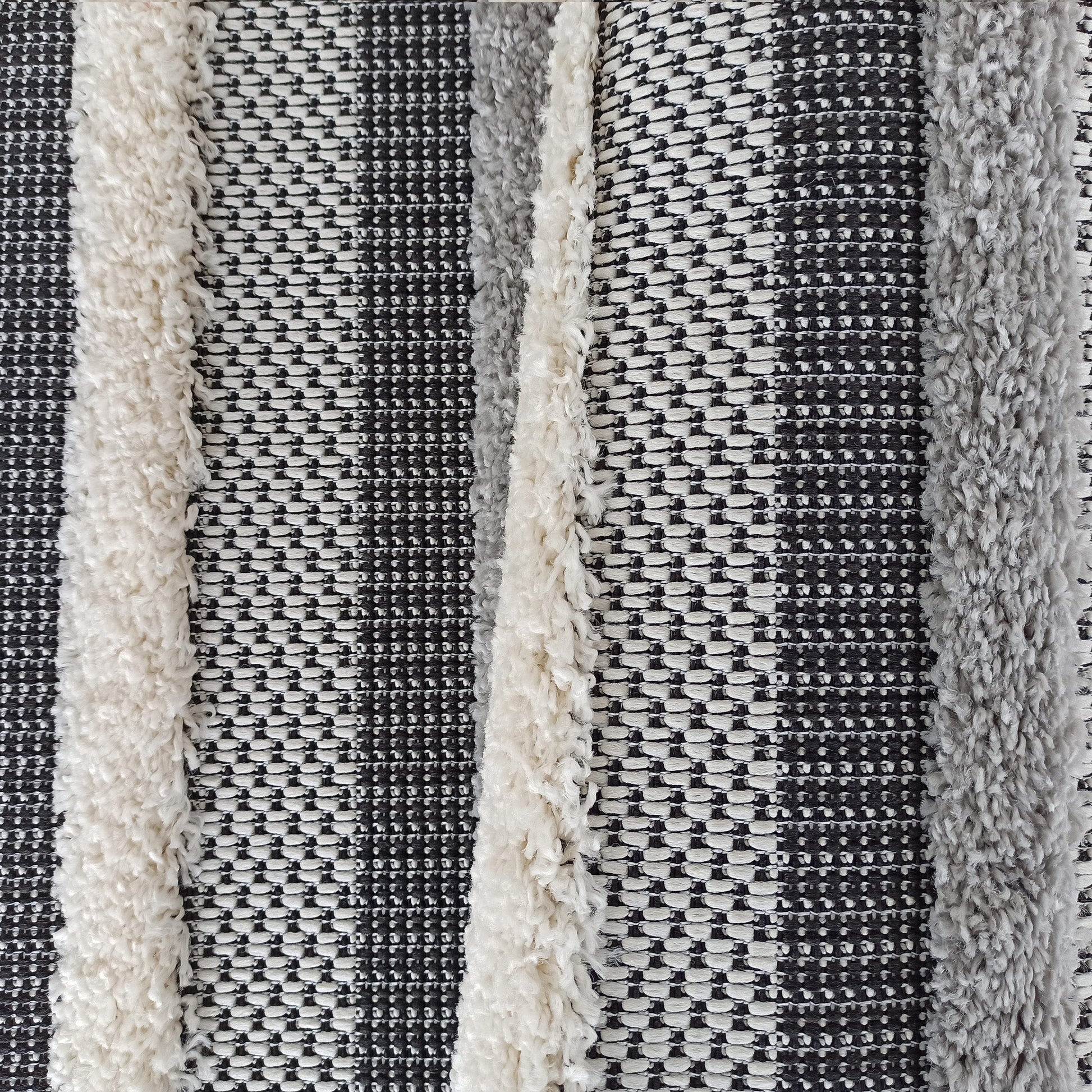 Tapis à rayures verticales alternant bandes tissées en motifs noirs et blancs avec des bandes à texture fourrure grise et crème