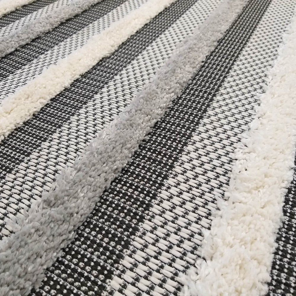 Gros plan d'un tapis à rayures noires et blanches à motif tissé et rayures épaisses et douces gris clair et blanc cassé