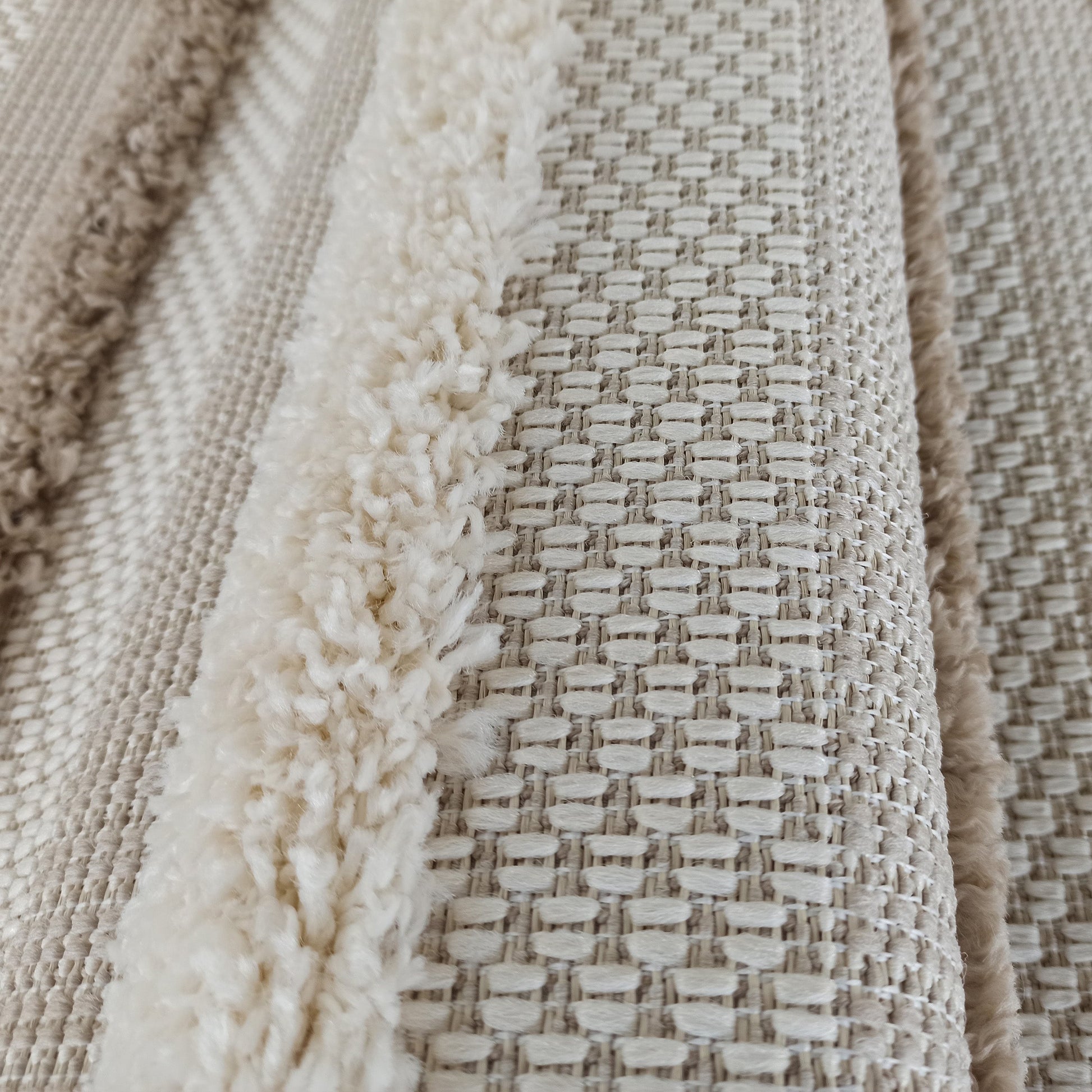 Tapis texturé beige clair et crème, présentant des bandes de longs poils doux alternant avec des motifs tissés en relief
