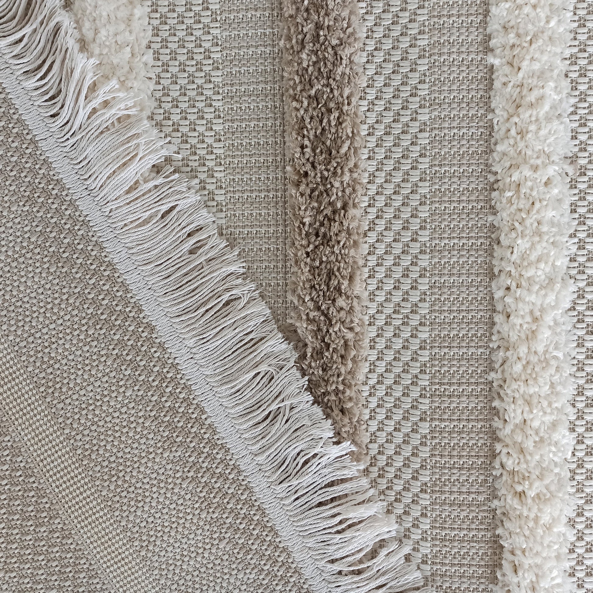 Tapis texturé avec des bandes shaggy crème et marron clair, et des franges blanches sur une base tissée beige