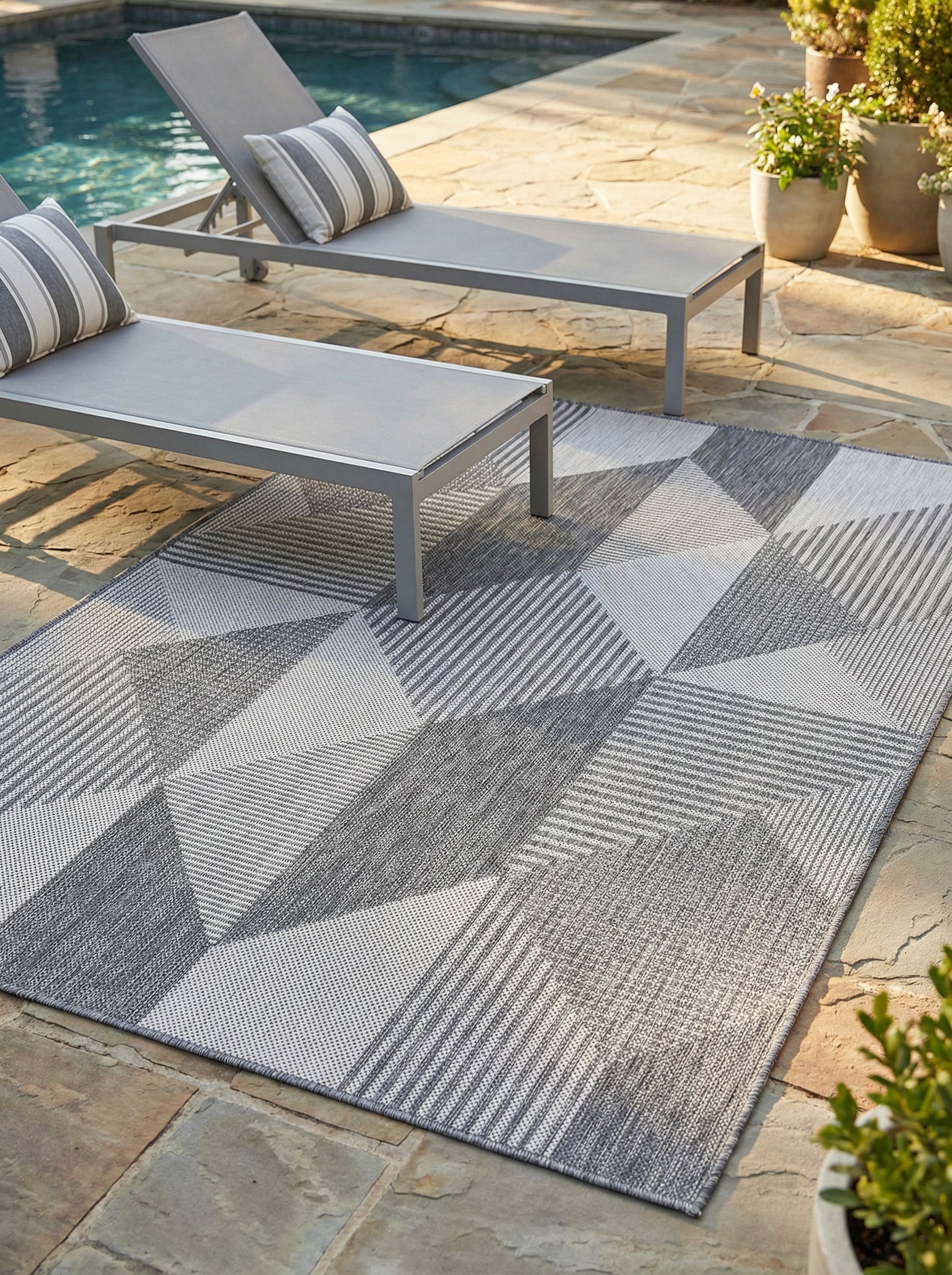 Tapis rectangulaire gris et blanc aux motifs géométriques texturés et rayures, sur une terrasse de piscine