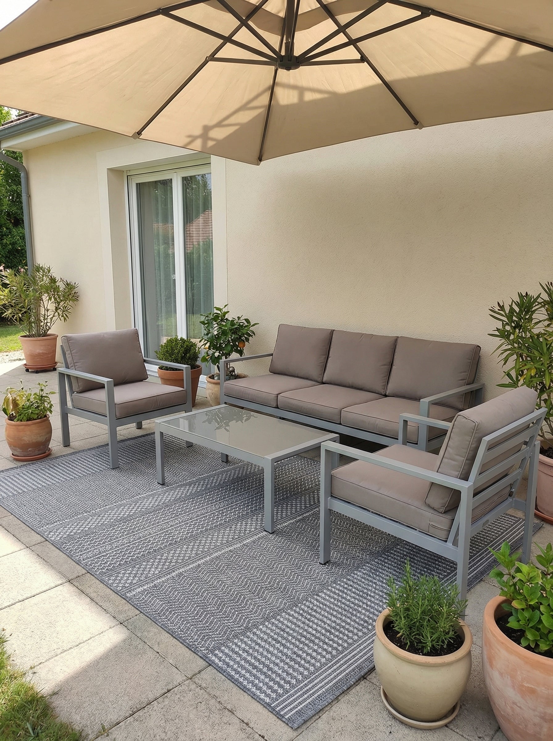 Tapis rectangulaire tissé gris clair et blanc à motifs géométriques zigzag et rayures, sur une terrasse aménagée