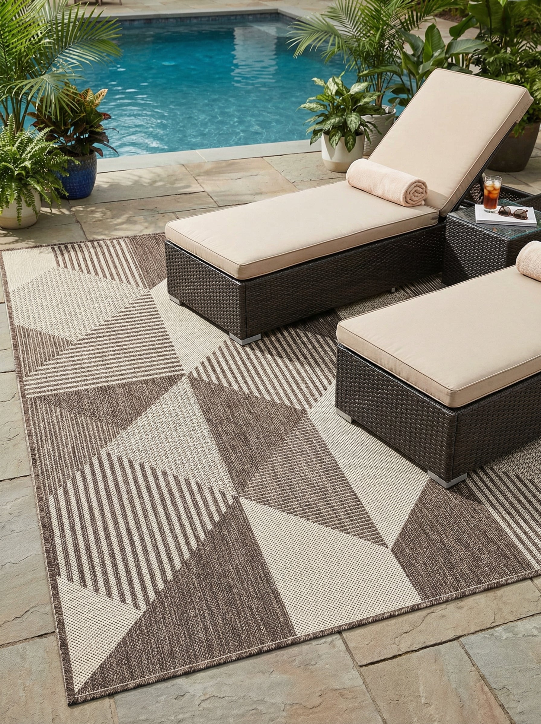 Tapis rectangulaire tissé marron et beige avec motifs géométriques de triangles et rayures, posé sur une terrasse près d'une piscine