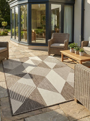 Tapis rectangulaire tissé crème et marron avec des motifs géométriques à triangles et rayures, posé sur une terrasse en pierre