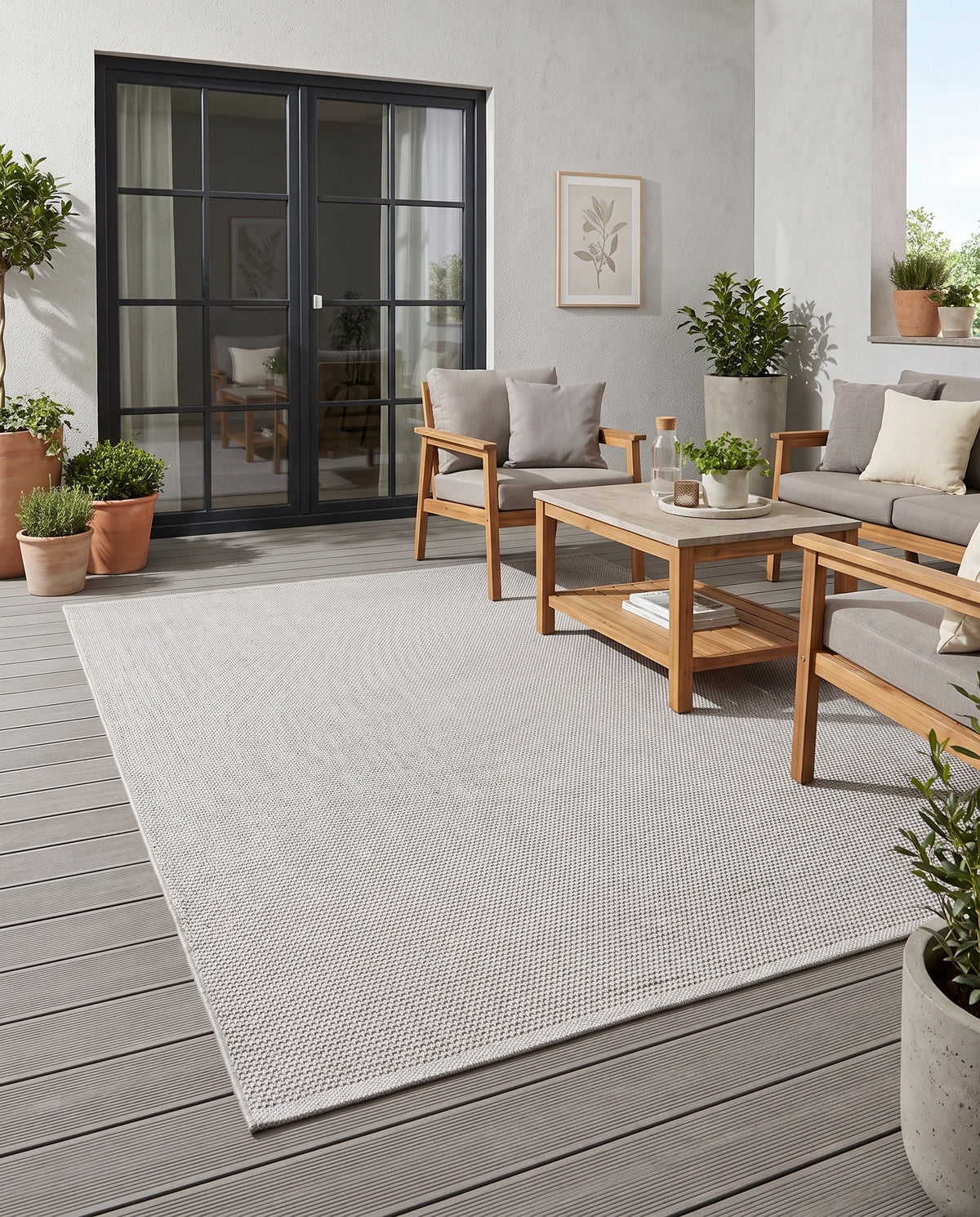 Le tapis gris clair, au tissage dense et discret, s'étend sur la terrasse pour un espace extérieur structuré