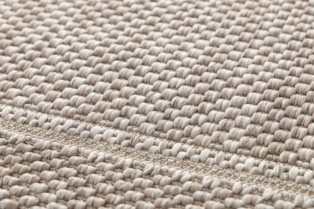 Tissage détaillé d'un tapis d'extérieur gris et ivoire, montrant des boucles régulières et une bande plate
