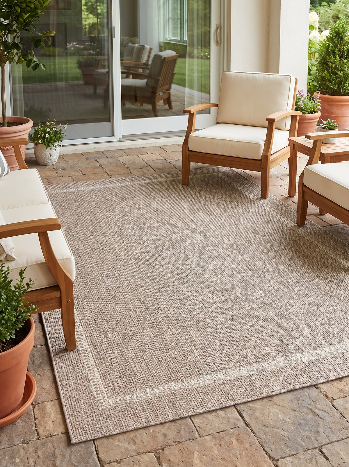 La bordure finement dessinée d'un tapis d'extérieur gris et ivoire, sur une terrasse ensoleillée