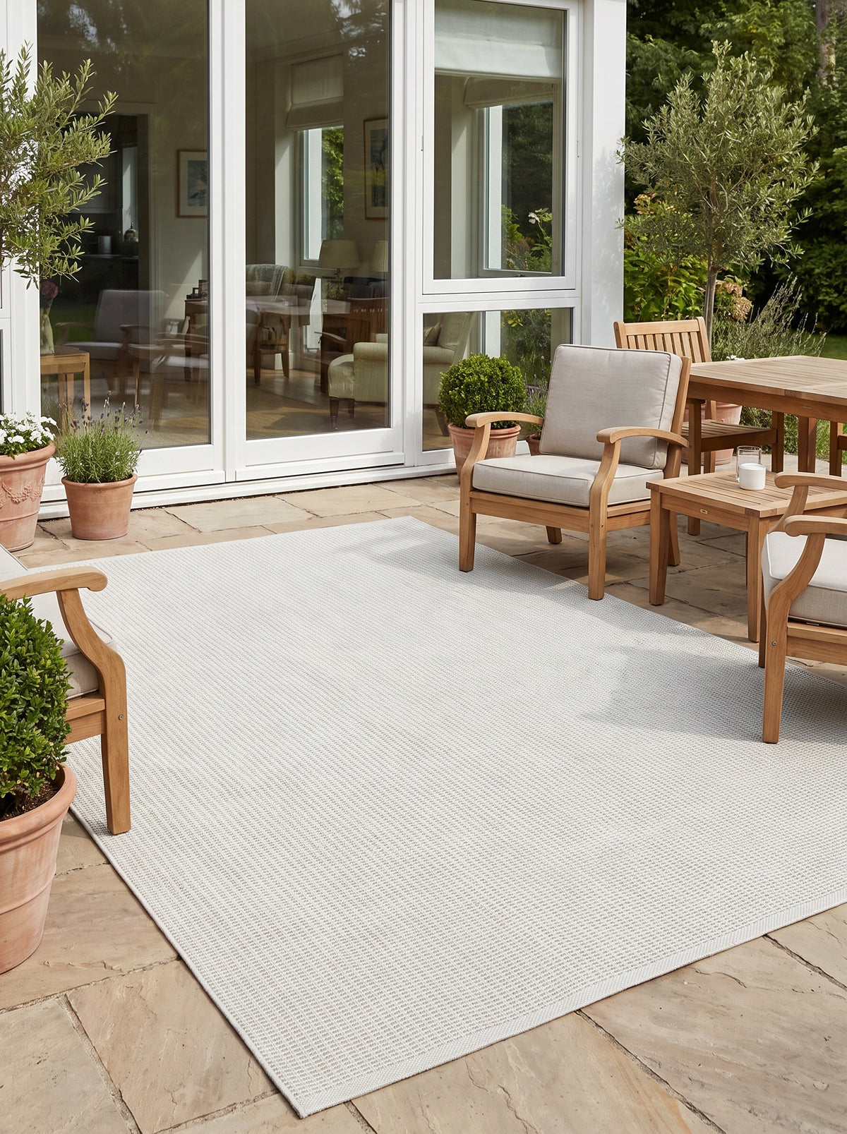 Son tissage régulier crée un motif délicat et ivoire sur ce tapis d'extérieur rectangulaire, posé sur une terrasse