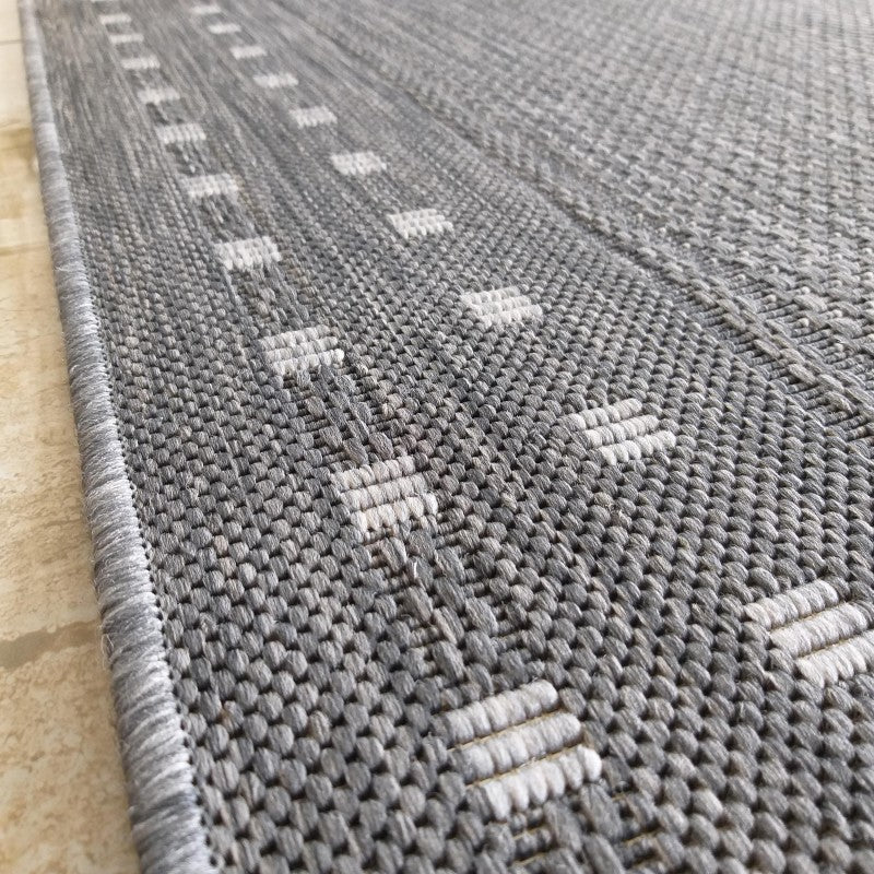 Tapis gris chiné tissé, orné de motifs géométriques discrets de petites barres horizontales claires