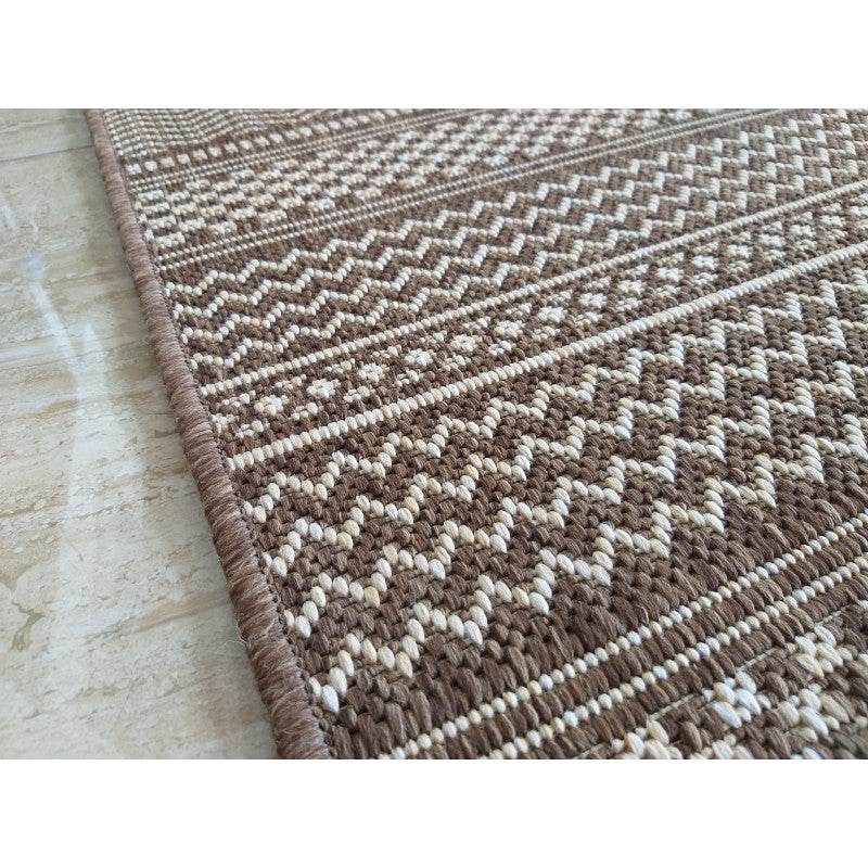 Tapis textile tissé marron et beige clair, avec des motifs géométriques en chevrons et formes de croix