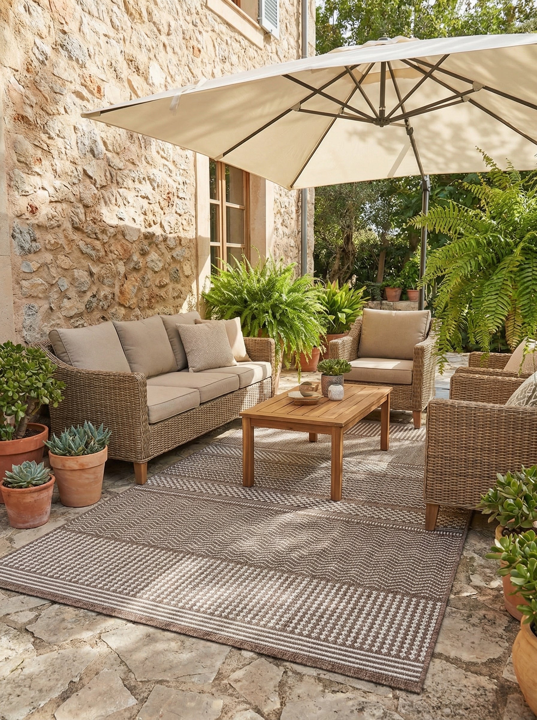 Tapis rectangulaire tissé marron et blanc cassé, à motifs géométriques chevrons et rayures, posé sur une terrasse extérieure