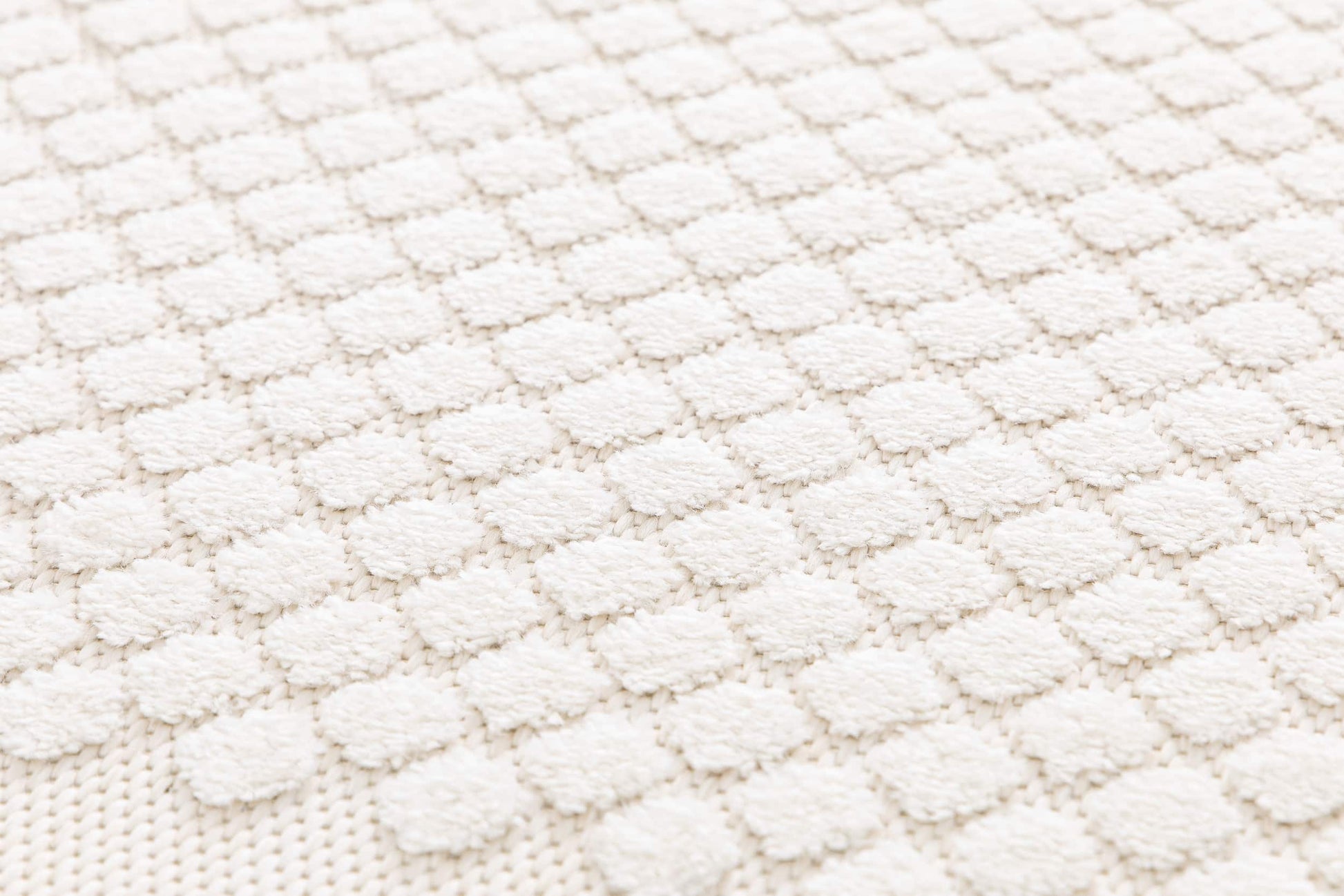 Tapis beige en relief, tissage à motifs ronds en relief. Texture douce et tactile, ambiance chaleureuse