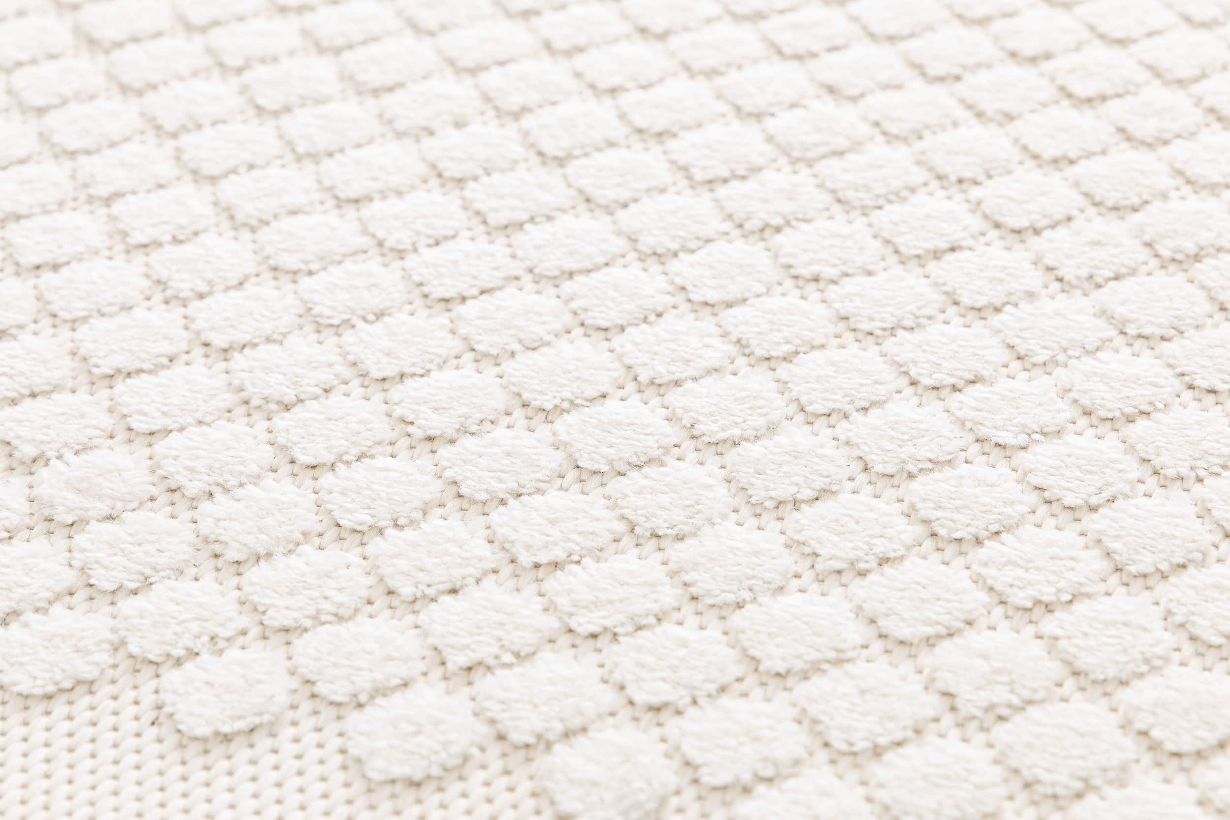 Tapis beige en relief, tissage à motifs ronds en relief. Texture douce et tactile, ambiance chaleureuse