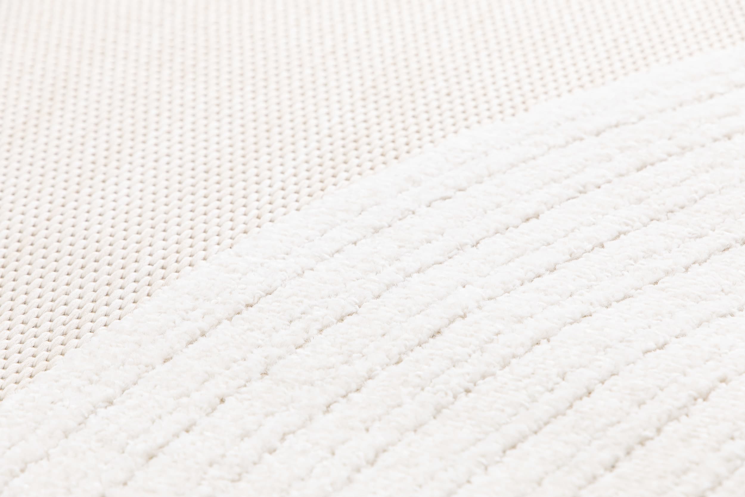Tapis beige et crème avec deux types de tissage. Relief en lignes et texture tactile douce. Ambiance cocooning