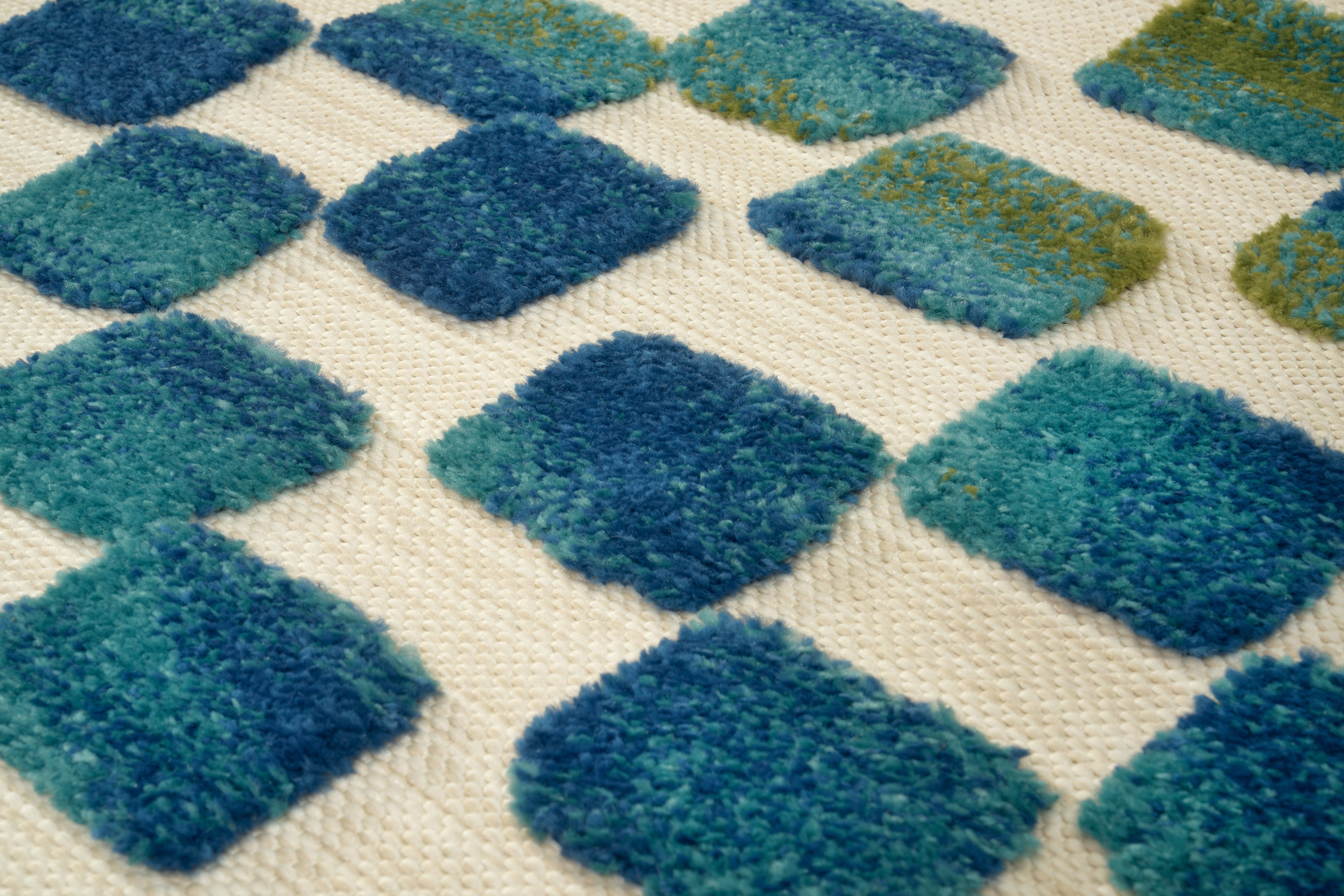 Tapis texturé, tissage serré, relief en losanges bleus et blancs. Aspect tactile duveteux, ambiance douce et chaleureuse
