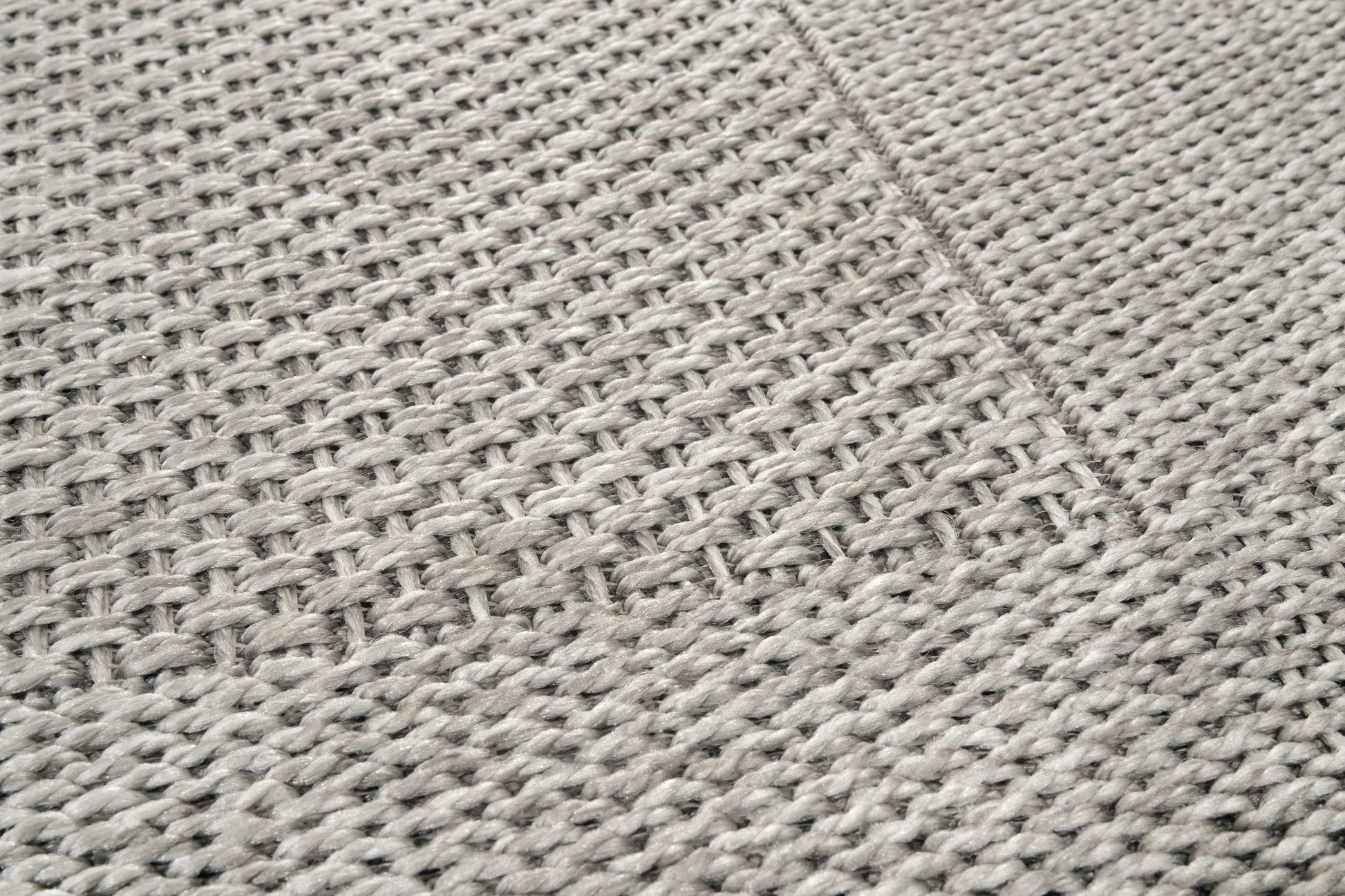 Tapis rectangulaire tissé en relief, texture tactile. Tissage en chevrons, couleurs gris et perle. Ambiance sobre