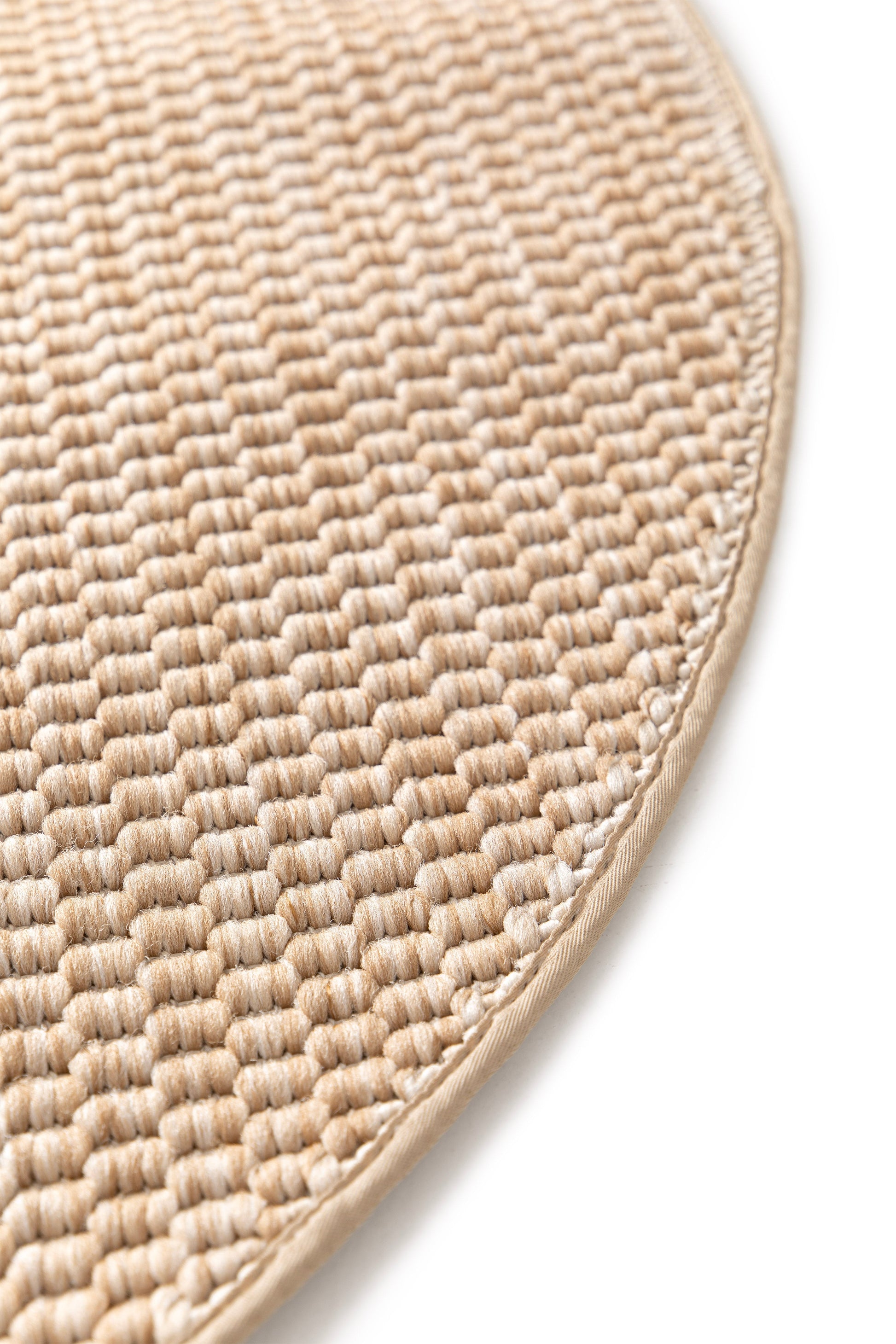 Bordure de tapis beige clair, finition cousue. Tapis rond de couleur beige et ambre