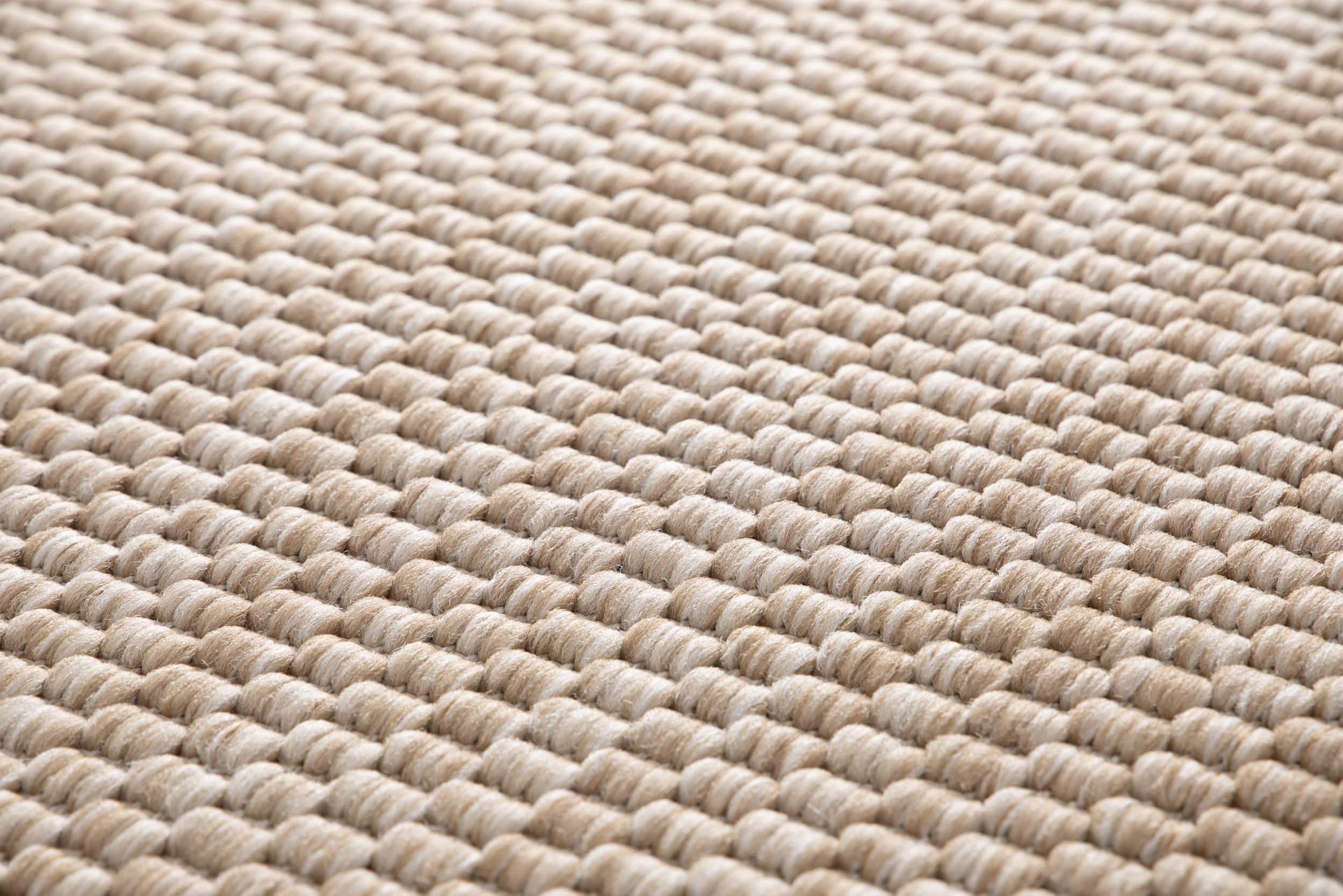 Tapis tissé à relief, texture bouclée. Aspect tactile doux, couleurs beige et ambre