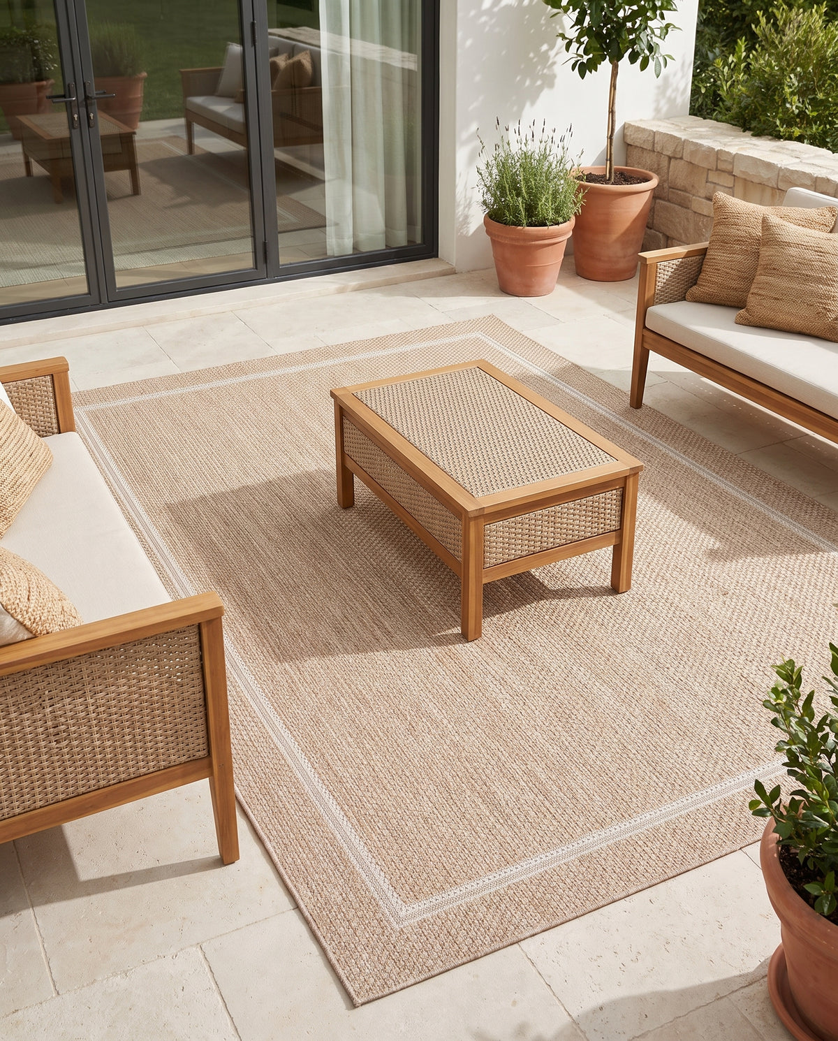 Sable et ivoire, un tapis extérieur rectangulaire au tissage bouclé et son motif de cadre, sur une terrasse
