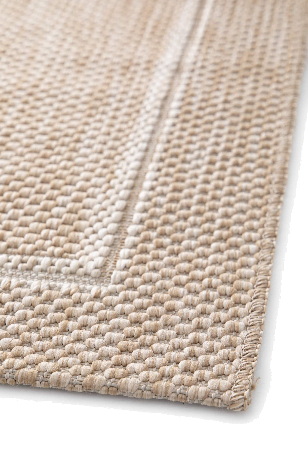 Le tissage bouclé sable et ivoire d'un tapis d'extérieur, montrant le relief du motif de cadre et la lisière du bord
