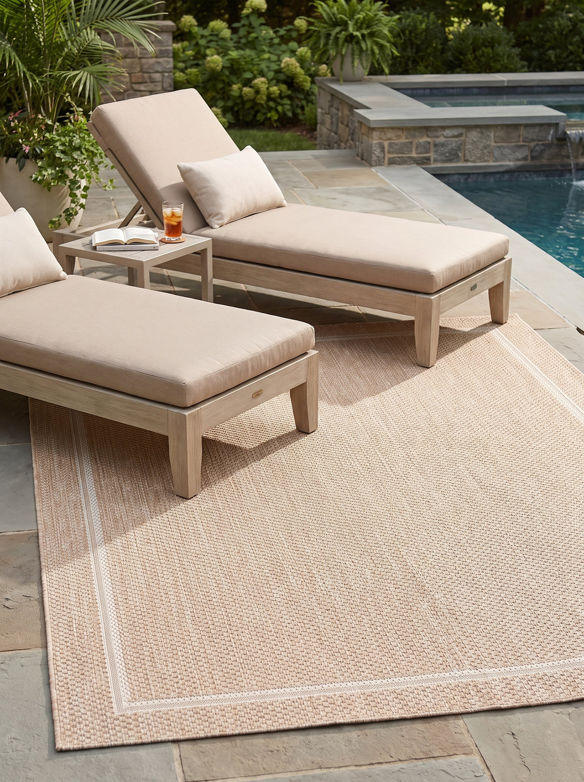 Le motif de cadre ivoire d'un tapis d'extérieur rectangulaire sable au tissage bouclé, posé sur une terrasse