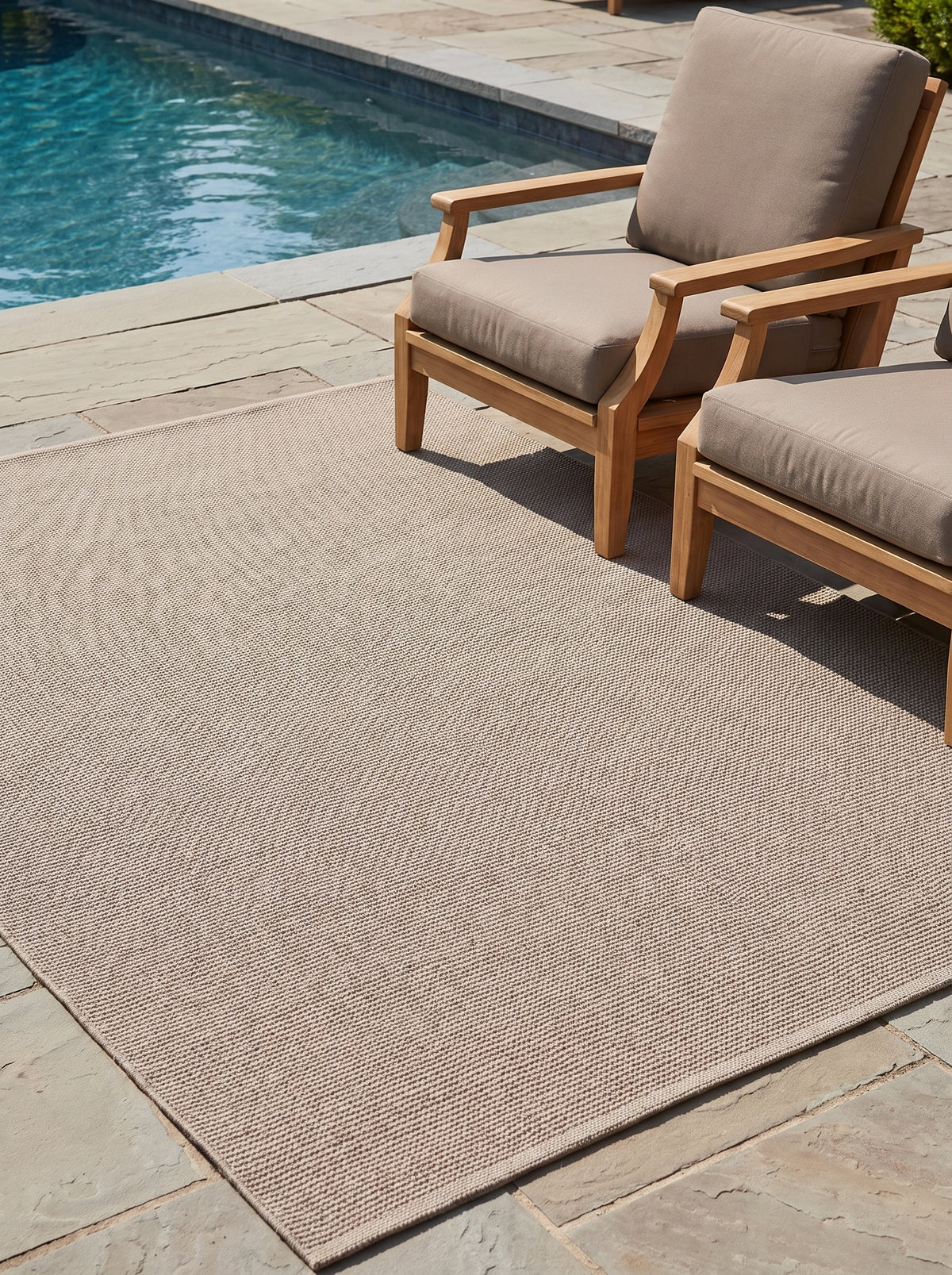 Un tapis d'extérieur taupe chaud, avec sa surface finement texturée, habille une terrasse près de la piscine