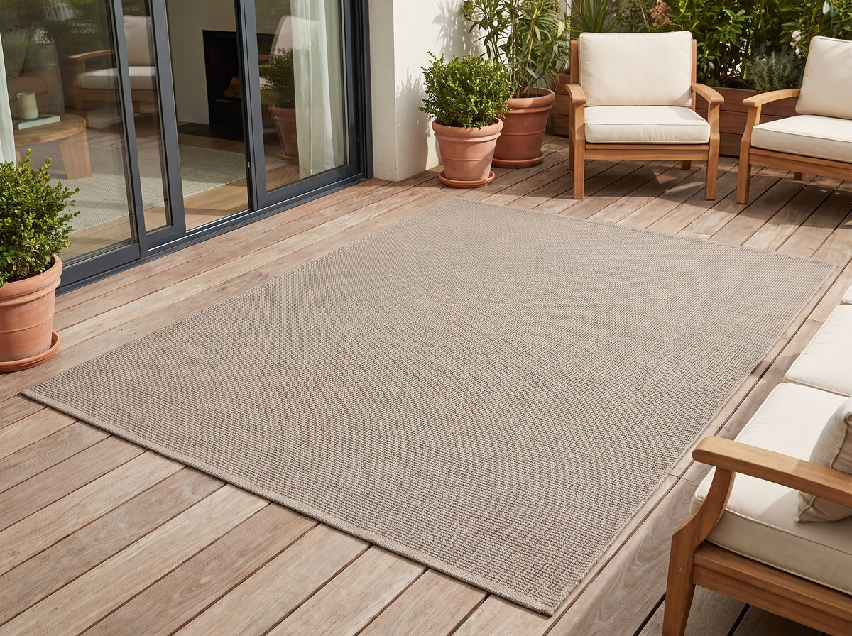 Le taupe chaud de ce tapis d'extérieur finement tissé réchauffe l'atmosphère d'une terrasse en bois