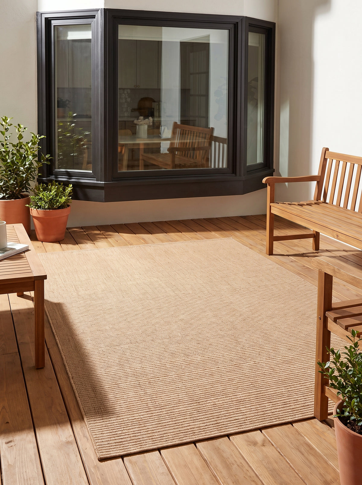 Fine horizontal ribs of a light terracotta rectangular rug visible on a wooden terrace