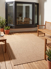 Les fines côtes horizontales d'un tapis rectangulaire terracotta clair sont visibles sur une terrasse en bois