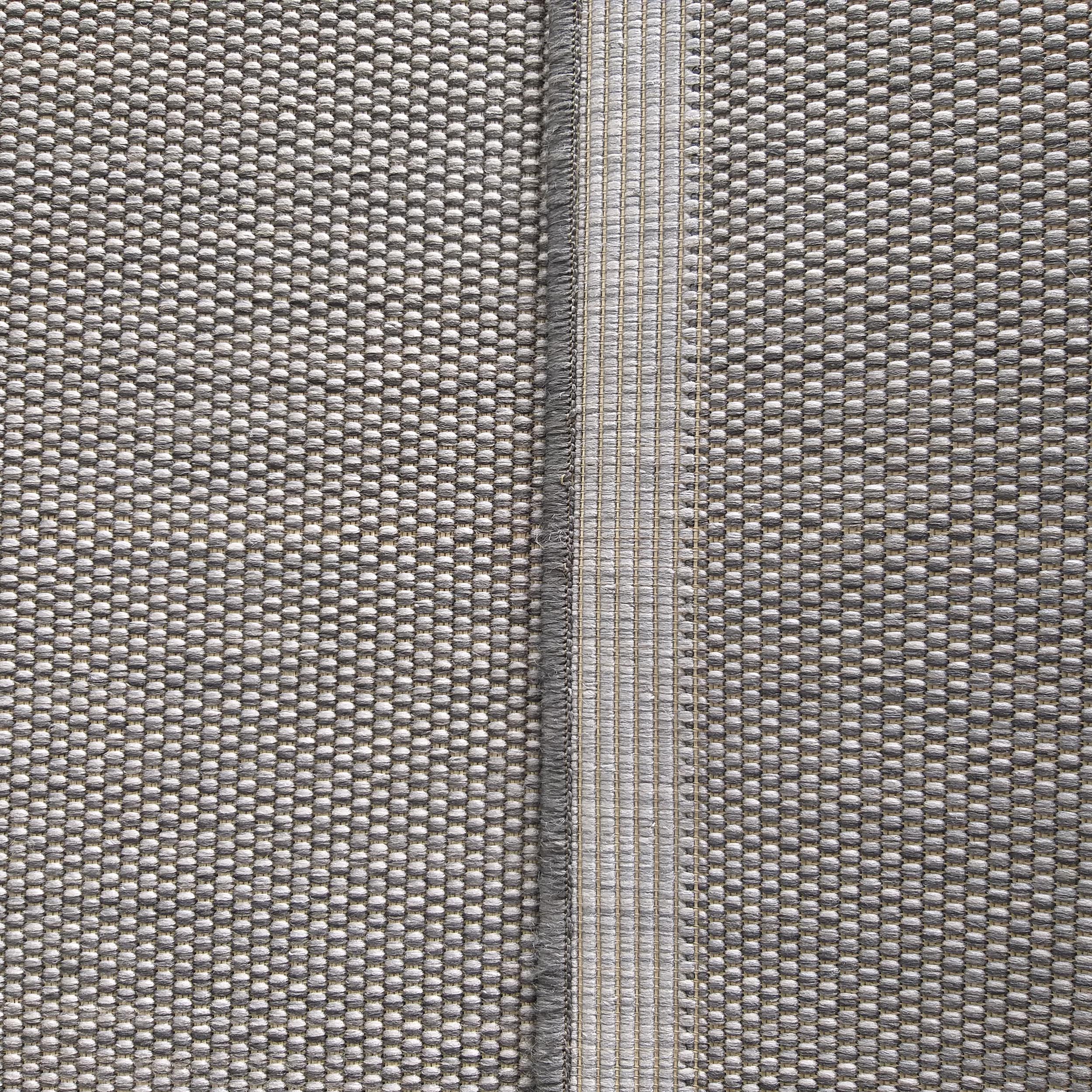 Tapis tissé gris présentant une texture bouclée et une bande centrale verticale au tissage plus plat