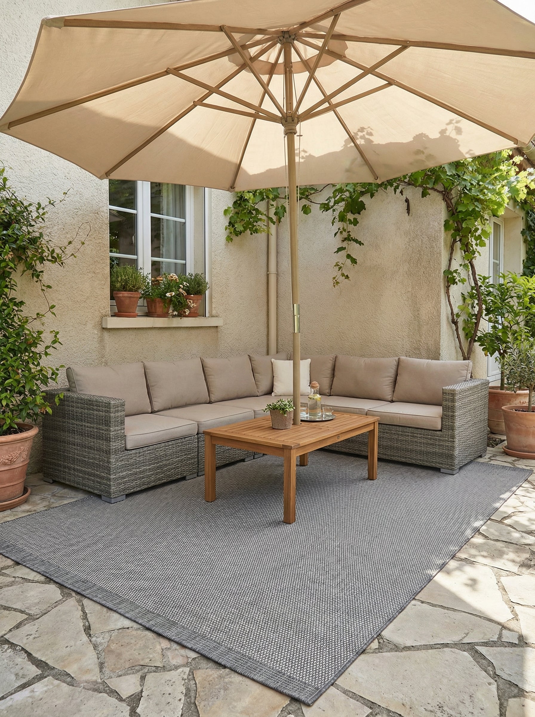 Tapis rectangulaire gris chiné à la texture tissée, posé sur une terrasse aménagée avec un salon de jardin
