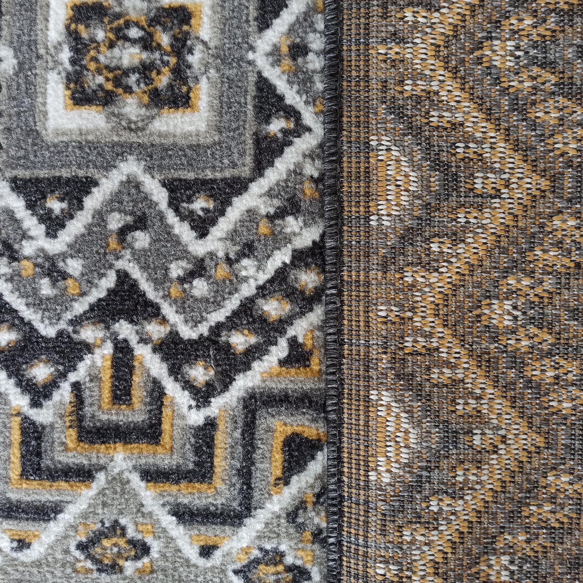 Tapis à motifs géométriques en gris, noir, blanc et jaune doré, avec une face touffetée et un envers tissé visible