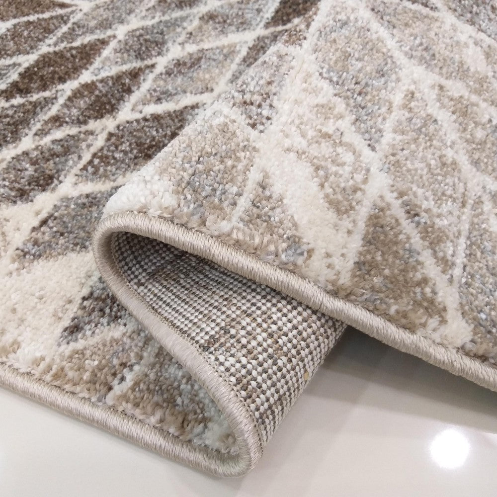 Tapis texturé beige et marron clair avec un motif géométrique abstrait, montrant le dessus et l'envers tissé roulé