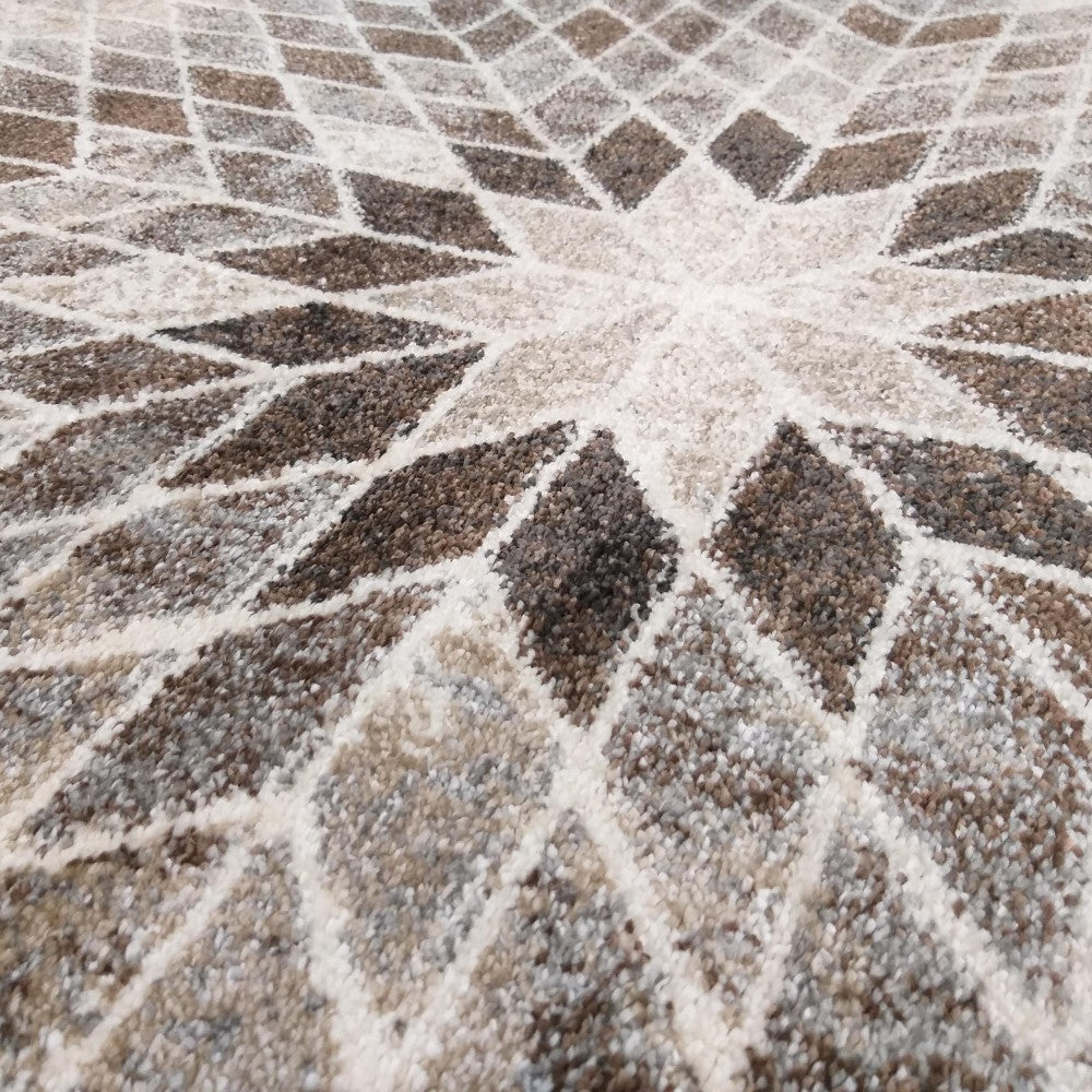 Tapis aux motifs géométriques en losanges rayonnant, dans des nuances de blanc cassé, beige et marron. Sa surface est texturée